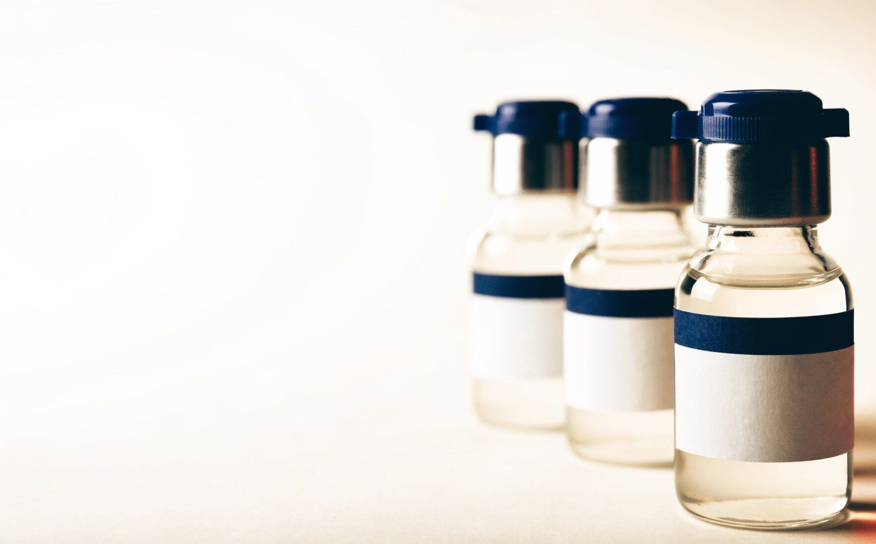 Laboratory vials with navy caps on a parchment surface